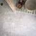 Bathroom floor featuring Essentials Terrazzo Stone Avorio 60x120cm terrazzo effect porcelain tiles, styled with a curved vanity clad in striped pastel tiles, a round basin, and brushed brass drainage detail.