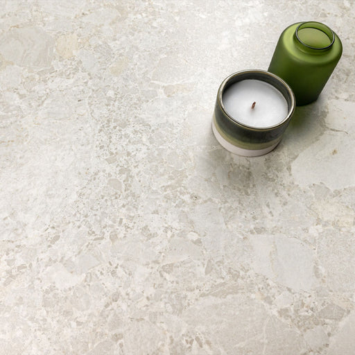 Kitchen surface featuring Essentials Terrazzo Stone Blanca 60x120cm terrazzo effect porcelain tiles, styled with a ceramic candle and green glass vessel, highlighting soft white and beige stone-inspired variation.