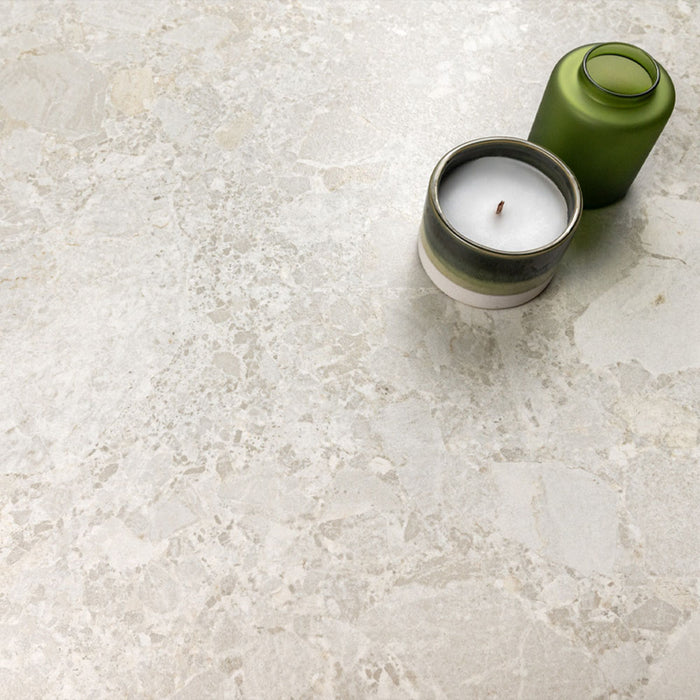 Kitchen surface featuring Essentials Terrazzo Stone Blanca 60x120cm terrazzo effect porcelain tiles, styled with a ceramic candle and green glass vessel, highlighting soft white and beige stone-inspired variation.