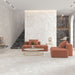 Living room interior featuring Essentials Terrazzo Stone Blanca 60x120cm terrazzo effect porcelain floor tiles, paired with matching wall surfaces, dark terrazzo feature shelving, and soft coral seating for a contemporary, design-led space.