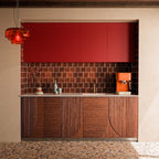 Stuzzi Amber 60cm x 120cm terrazzo effect tiles with a 4D brushed finish, bringing warm amber and earthy tones to the floor, paired with rich red cabinetry and deep brown wall tiles.