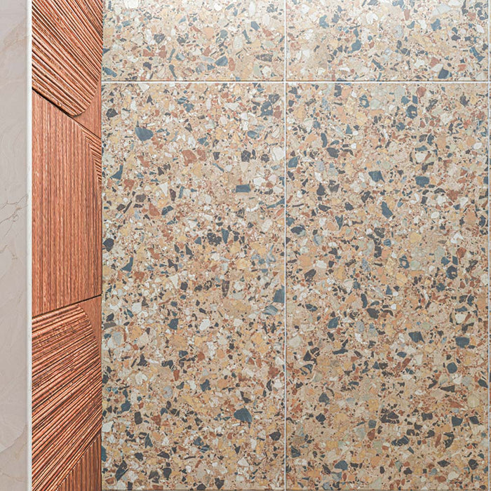 Stuzzi Amber 60cm x 120cm terrazzo effect tiles with a 4D brushed finish, highlighting the detailed mix of warm amber, terracotta, cream and contrasting darker fragments.