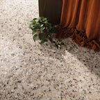Overhead view of the Stuzzi Dolmia 60x120cm terrazzo style porcelain floor tiles, featuring a warm beige base with a blend of cream, taupe, brown, grey and charcoal stone fragments. The realistic 4D brushed finish adds texture and depth, creating a timeless terrazzo effect in a contemporary interior.