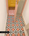Entrance featuring Supernova Decor Rose 20cm x 20cm tiles in soft pink with a contrasting white star motif, paired with a yellow door, pink woodwork and adjoining geometric patterned floor tiles.