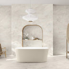 Bathroom interior featuring Taj Mahal Matt 60 × 120cm marble effect porcelain wall and floor tiles, showcasing soft cream tones with gentle, flowing veining. The larger format enhances the sense of space, creating a seamless, spa-like setting complemented by warm wood accents and soft, natural light.