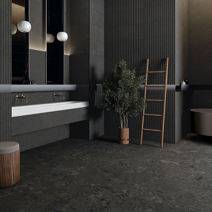 Modern bathroom featuring Terrazerri Terrazzo Black 60x60cm porcelain tiles on the floor and walls. The dark charcoal terrazzo effect creates a bold, contemporary look, paired with fluted wall panels, a floating white vanity, timber accents and soft globe lighting for a sophisticated, luxurious finish.