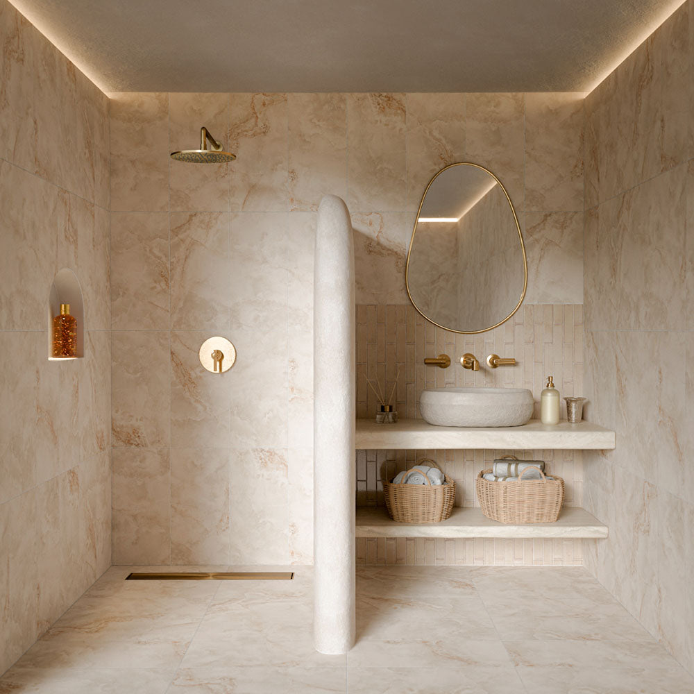 Luxury bathroom featuring Thebes Ivory honed matt onyx effect porcelain tiles in 60cm x 120cm. Large-format ivory marble effect wall and floor tiles with soft natural veining create a warm, spa-inspired bathroom, complemented by a cream brick tile splashback and elegant brass fixtures.