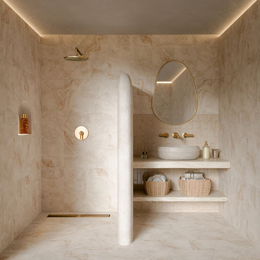 Luxury bathroom featuring Thebes Ivory honed matt onyx effect porcelain tiles in 60cm x 120cm. Large-format ivory marble effect wall and floor tiles with soft natural veining create a warm, spa-inspired bathroom, complemented by a cream brick tile splashback and elegant brass fixtures.
