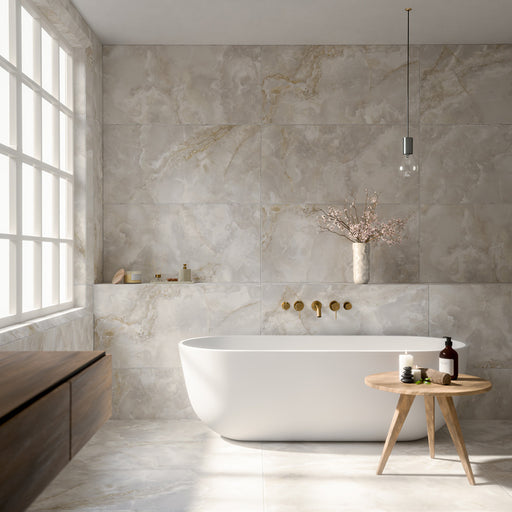 Luxury bathroom featuring Thebes White honed matt onyx effect porcelain wall and floor tiles in a large-format 60cm x 120cm design, paired with a freestanding bath, brushed brass fittings, floating wood vanity, soft natural light and contemporary spa-inspired styling.