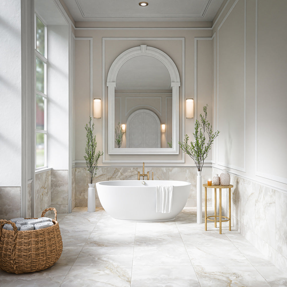 Elegant bathroom featuring Thebes White honed matt onyx effect porcelain wall and floor tiles in a 60cm x 60cm format, paired with a freestanding bath, classic wall panelling, an arched mirror, brushed brass fittings and soft neutral styling for a timeless luxury look.