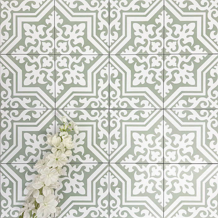 Flat lay of London Streets Thornton Place Sage Green 20cm x 20cm Victorian Moroccan style tiles arranged in a repeating pattern, featuring intricate white motifs on a sage green background with decorative white flowers.