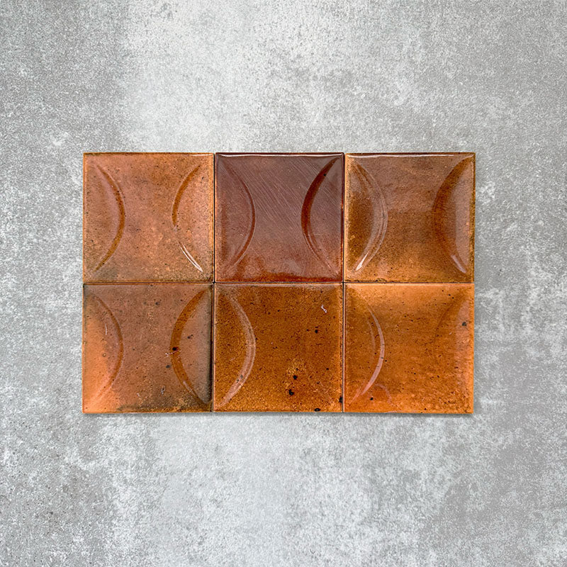 Close-up of Saigon Amber Decor Square Wall tiles, featuring Moroccan-style 10 × 10cm glossy ceramic tiles in warm amber tones with a curved decorative relief pattern.