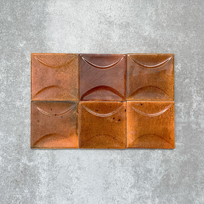 Close-up of Saigon Amber Decor Square Wall tiles, featuring Moroccan-style 10 × 10cm glossy ceramic tiles in warm amber tones with a curved decorative relief pattern.
