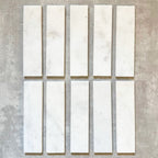 Fayrouz White 5x20cm natural marble tiles with a honed finish, featuring a soft white base with subtle grey veining, arranged in a neat grid to highlight natural variation and tonal consistency.