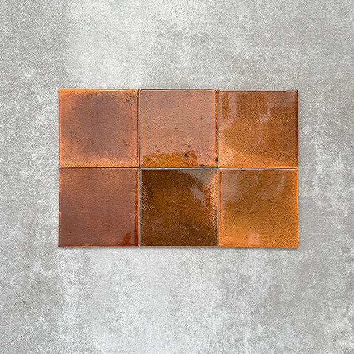 Close-up of Saigon Amber Square Wall tiles in a Moroccan-inspired style, 10 × 10cm glossy ceramic tiles with warm amber and copper colour variations.