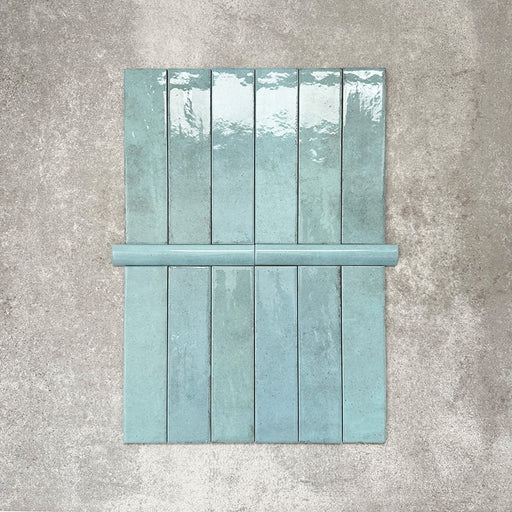 Nomad Aquamarine bullnose pencil border ceramic tiles in a 3 × 20cm format, shown alongside matching brick tiles, featuring a glossy finish and soft blue-green tones for a coordinated industrial-style wall detail.