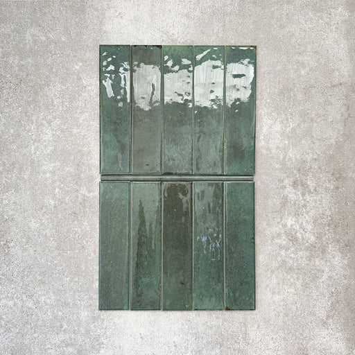 Allegra Green Gloss pencil bullnose border tiles in a 1.2 × 30cm ceramic format, shown arranged with matching brick tiles to highlight the coordinating deep green colour, subtle tonal variation and smooth gloss finish against a neutral textured background.