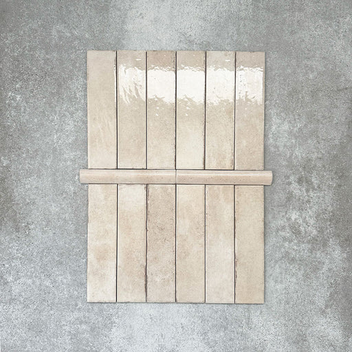 Nomad Oatmeal bullnose pencil border ceramic tiles in a 3 × 20cm format, shown with matching brick tiles to highlight the warm oatmeal tone, gloss finish and rounded edge detail.