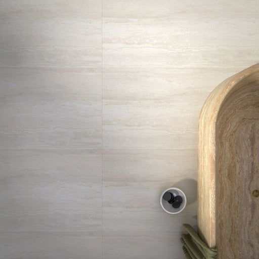 Modern bathroom featuring Trevi Stone matt porcelain floor tiles paired with a green and ivory herringbone feature wall, a freestanding stone bath and brushed brass fittings, creating a calm, spa-inspired interior with natural tones.