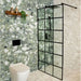 Contemporary bathroom featuring Venice Emerald matt terrazzo effect porcelain wall tiles paired with Venice Pearl terrazzo effect tiles, complemented by a black crittall shower screen, black brassware and warm wooden accents for a striking modern design.