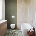 Luxury bathroom featuring Venice Emerald matt terrazzo effect porcelain floor tiles with bold stone chips, complemented by olive green cabinetry, textured stone effect wall tiles and a freestanding bath for a contemporary spa-inspired design.