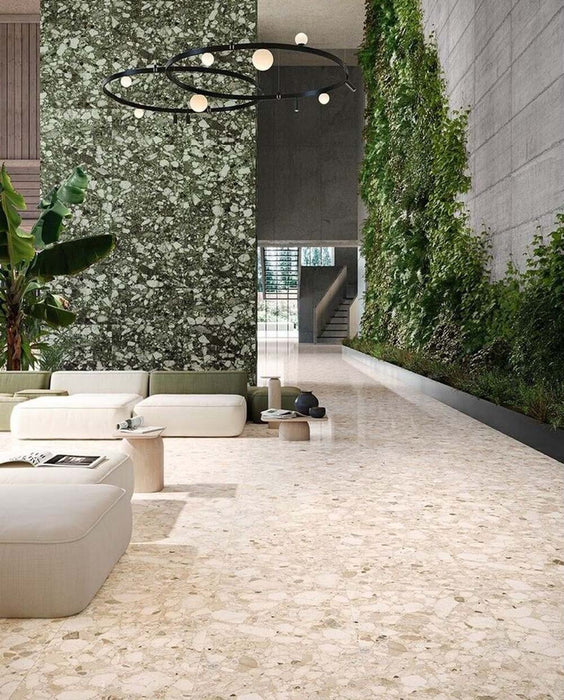 Spacious contemporary interior featuring Venice Ivory matt terrazzo effect porcelain tiles in a 60 x 120cm format, paired with a striking green terrazzo feature wall, indoor planting and modern minimalist furnishings.