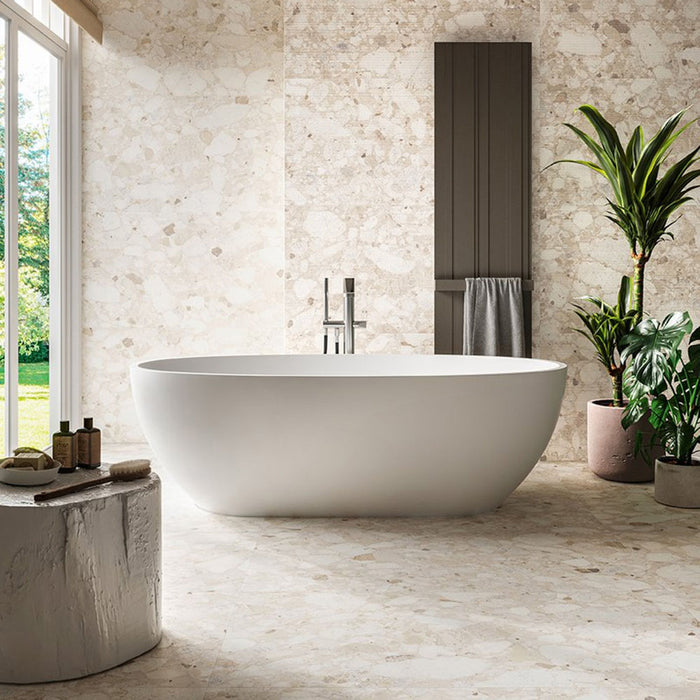 Luxury bathroom featuring Venice Ivory matt terrazzo effect porcelain wall and floor tiles, paired with a freestanding bath, soft neutral tones and lush greenery to create a bright, contemporary spa-inspired space.