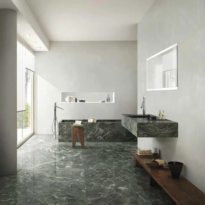 Bathroom interior featuring Verde Apia Matt Green Marble effect 60 × 120cm porcelain wall and floor tiles, styled with a built-in bath, floating vanity, and soft natural light highlighting rich green tones and subtle veining.