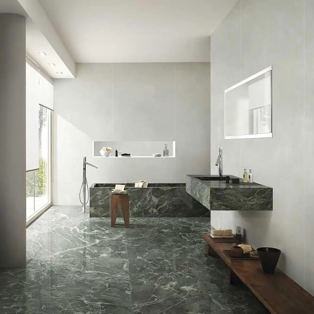 Bathroom interior featuring Verde Apia Matt Green Marble effect 60 × 120cm porcelain wall and floor tiles, styled with a built-in bath, floating vanity, and soft natural light highlighting rich green tones and subtle veining.