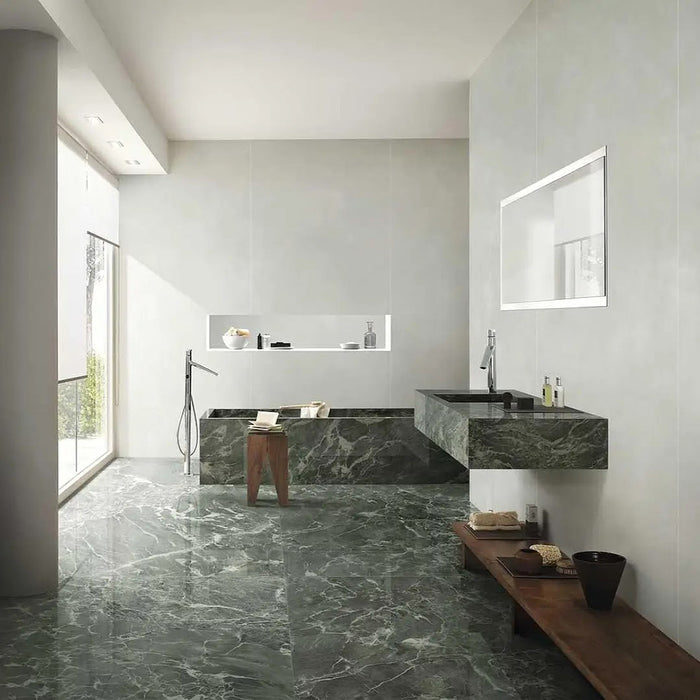 Bathroom interior featuring Verde Apia Matt Green Marble effect 60 × 120cm porcelain wall and floor tiles, styled with a built-in bath, floating vanity, and soft natural light highlighting rich green tones and subtle veining.