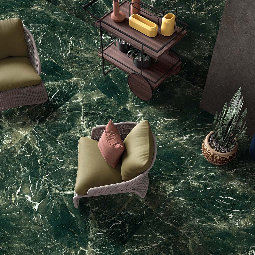 Living space featuring Verde Apia Polished Green Marble effect 60 × 120cm porcelain floor tiles, styled with woven seating, wooden trolley table, and rich green tones with striking natural veining.