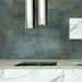 Contemporary kitchen featuring Verde Copper Oxide 30cm x 60cm metallic effect wall tiles, paired with marble-effect cabinetry, chrome extractor hood and sleek worktops for an industrial-inspired interior.