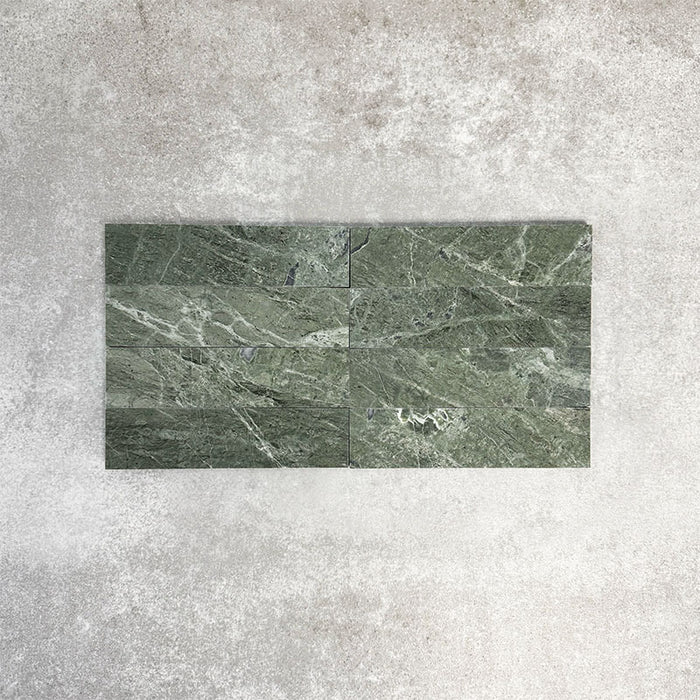 Arrangement featuring Fayrouz Verde 5x20cm natural marble tiles with a honed finish, laid in a horizontal brick pattern, showcasing rich green tones, natural veining and tonal variation against a neutral background.
