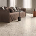 Contemporary living room featuring Verona Medium Sand concrete effect porcelain floor tiles with a terrazzo-inspired finish, complemented by a neutral linen sofa, warm earthy tones, minimalist furniture and soft natural light.