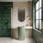 Bathroom featuring Verona Medium Sand 60cm x 60cm terrazzo concrete style porcelain tiles across the walls and floor, showcasing a warm neutral base with multicoloured terrazzo details, paired with deep green gloss brick tiles and a fluted sage green basin.