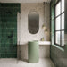 Bathroom featuring Verona Medium Sand 60cm x 60cm terrazzo concrete style porcelain tiles across the walls and floor, showcasing a warm neutral base with multicoloured terrazzo details, paired with deep green gloss brick tiles and a fluted sage green basin.