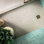 Verona Micro Sand 60cm x 60cm terrazzo concrete effect porcelain floor tiles, featuring a warm neutral base with subtle speckled detail, paired with aqua green wall tiles and brass shower fittings.