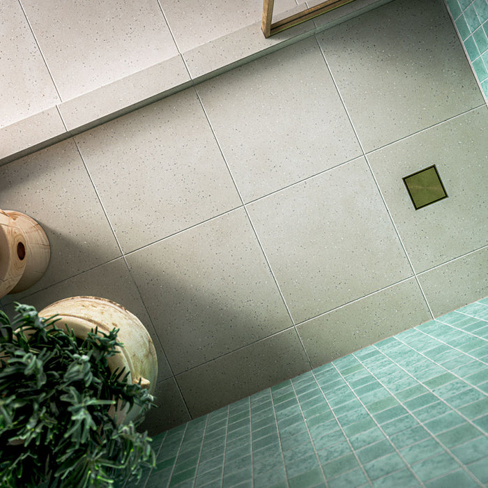 Contemporary walk-in shower featuring Verona Micro Sand 60cm x 60cm terrazzo effect porcelain wall tiles, paired with white floor tiles, brass shower fittings and an arched alcove for a Mediterranean-inspired bathroom.