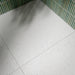 Bathroom interior featuring Verona Micro White 60 × 60cm terrazzo concrete-effect porcelain floor tiles, showcasing a soft white surface with delicate speckled detailing, paired with pale green mosaic wall tiles and warm brass fittings for a clean, contemporary finish.