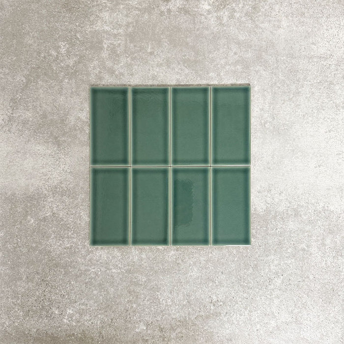 Close-up of Pimlico Golders Green 7.5 × 15cm ceramic tiles with a crackle glaze finish, showcasing deep green tones, subtle surface texture and a classic rectangular format for wall applications.