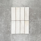 Close-up of Saigon White Brick Wall tiles in a Moroccan-style design, 5.1 × 16.1cm glossy ceramic tiles in soft white tones with subtle tonal variation, shown laid vertically.
