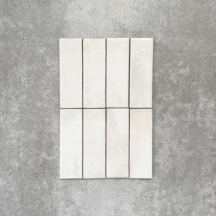 Close-up of Saigon White Brick Wall tiles in a Moroccan-style design, 5.1 × 16.1cm glossy ceramic tiles in soft white tones with subtle tonal variation, shown laid vertically.