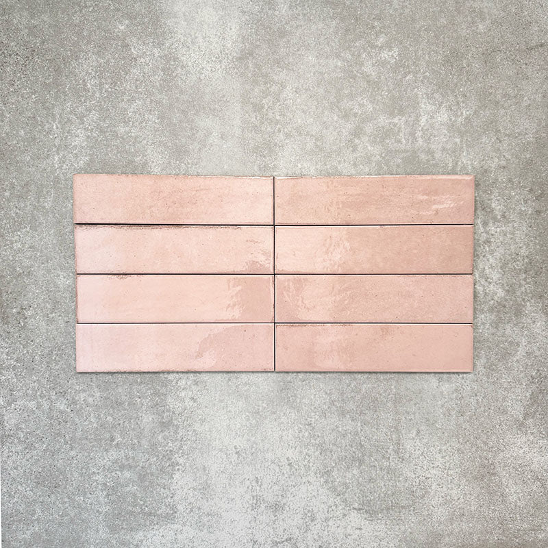 Nomad Rose brick wall tiles in a 6 × 24.6cm format, shown laid together to highlight the soft pink tone, gloss finish and subtle surface variation.
