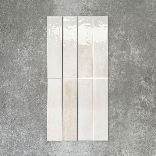 Allegra Blanca Gloss Brick ceramic tiles in a 6 × 25cm format, shown laid vertically to highlight the glossy white finish and subtle tonal variation of the handmade-style surface.