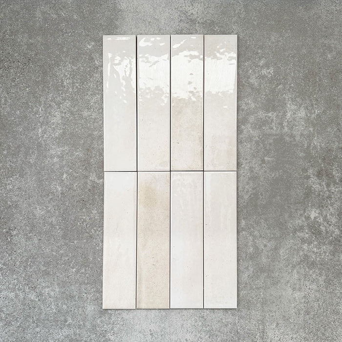 Allegra Blanca Gloss Brick ceramic tiles in a 6 × 25cm format, shown laid vertically to highlight the glossy white finish and subtle tonal variation of the handmade-style surface.