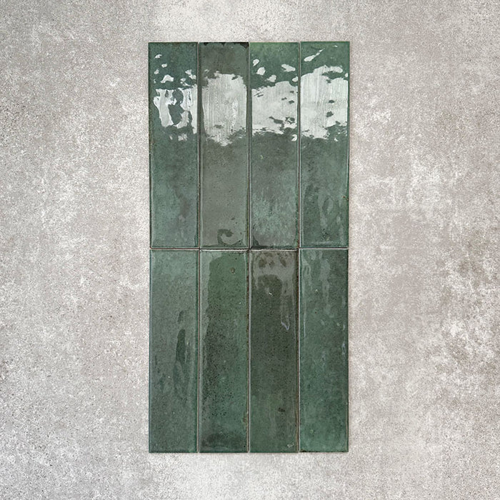 Allegra Green Gloss brick ceramic tiles in a 6 × 25cm format, shown in a vertical layout to highlight the glossy surface, deep green colour and natural tonal variation across each tile.