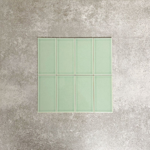 Close-up of Pimlico Lime Green 7.5 × 15cm ceramic tiles with a crackle glaze finish, showcasing soft green tones, subtle surface texture and a smooth rectangular format ideal for bathroom and kitchen walls.