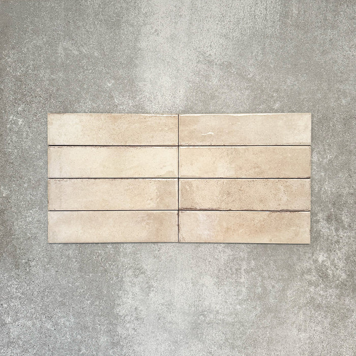 Nomad Oatmeal brick wall tiles in a 6 × 24.6cm format, shown laid together to highlight the warm neutral tone, gloss finish and subtle surface variation.