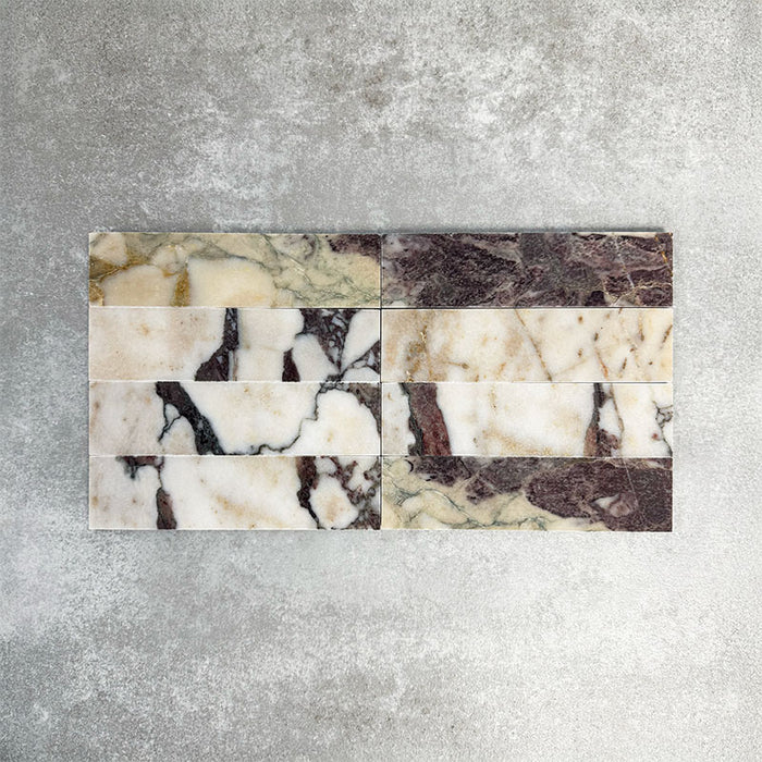 Fayrouz Viola 5x20cm natural marble tiles with a honed finish, featuring a white base with bold burgundy and warm-toned veining, arranged in a neat grid to highlight natural variation and distinctive stone detail.