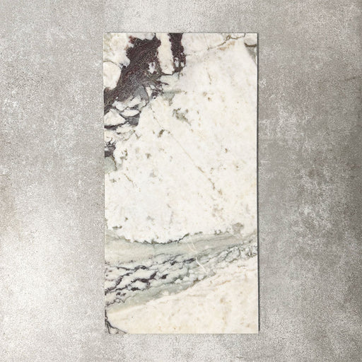 Fayrouz Viola 30.5x61cm natural marble tiles with a honed finish, featuring a warm ivory base with bold burgundy and green veining, shown as a single tile sample against a neutral textured backdrop.